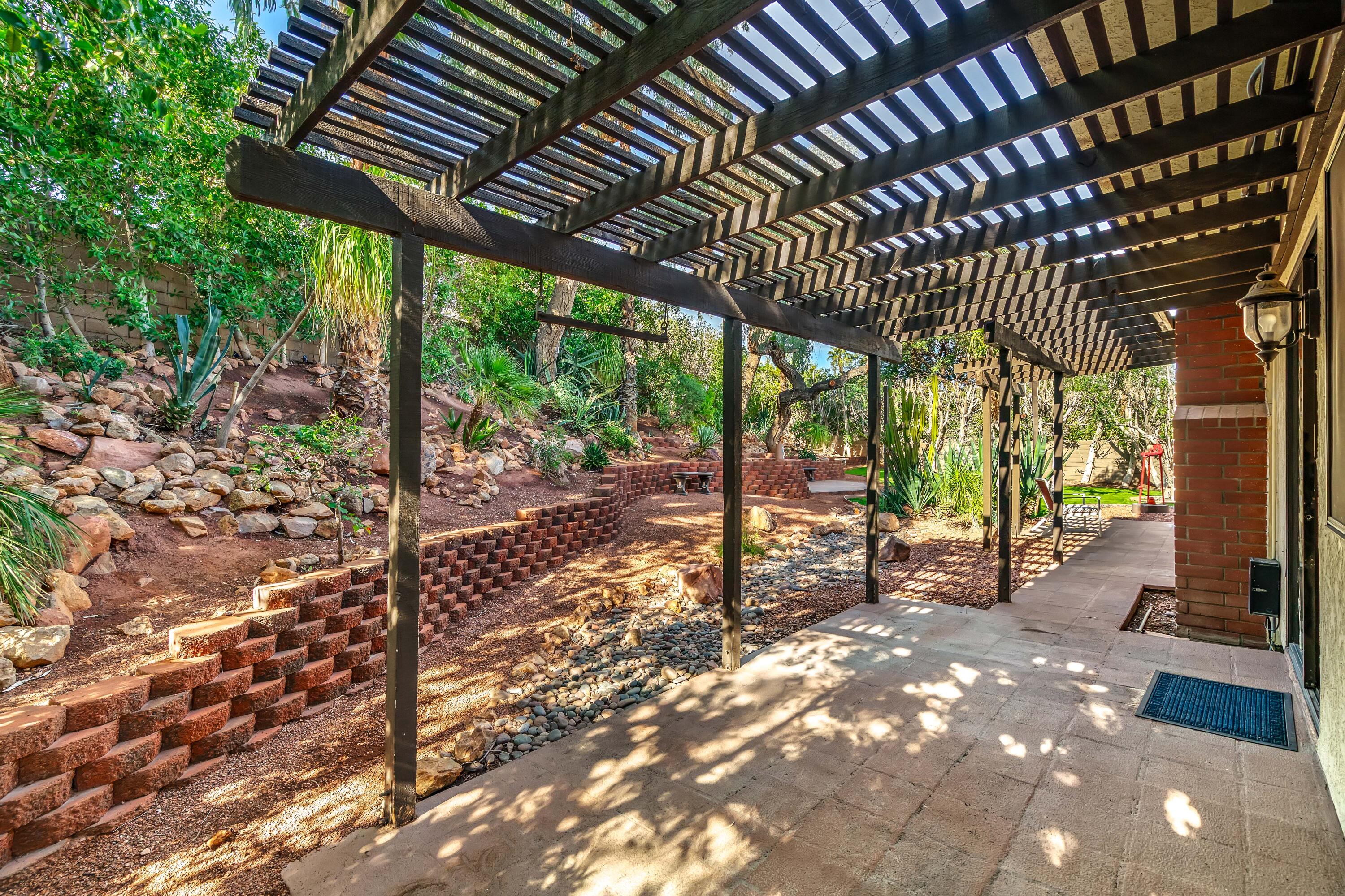 37 Santo Domingo Drive Rancho Mirage, CA 92270 - Photo 38 of 49 a view of a patio with table and chairs under an umbrella with a large tree