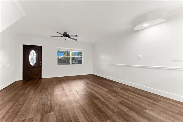 a view of an empty room with wooden floor and a window
