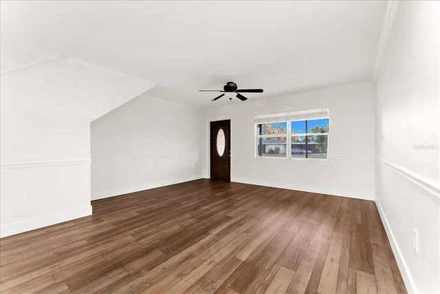a view of a livingroom with a ceiling fan & wooden floor