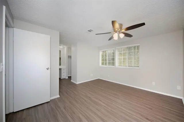 a view of a room with wooden floor and a ceiling fan