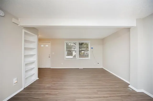 a view of an empty room with wooden floor and closet
