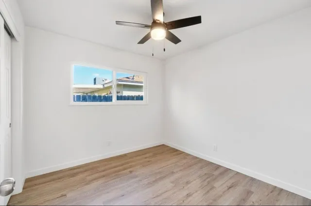 an empty room with wooden floor and ceiling fan