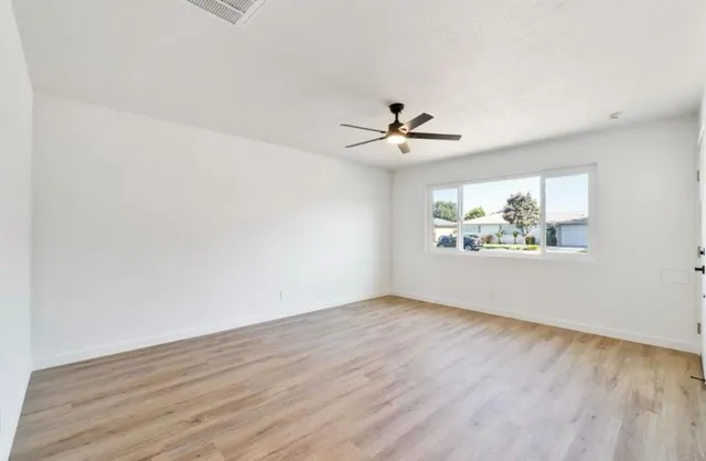an empty room with wooden floor and chandelier fan