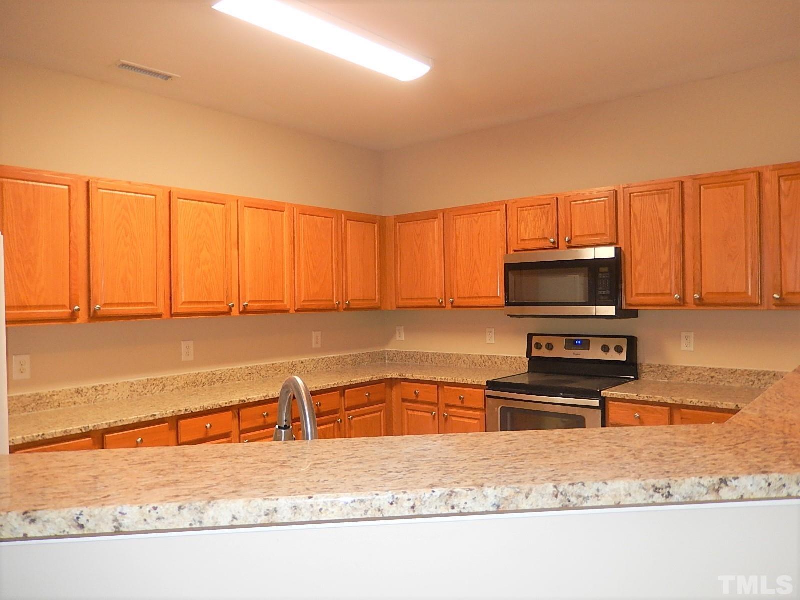 101 Olvera Way Holly Springs, NC 27540 - Photo 11 of 25 a kitchen with stainless steel appliances granite countertop a sink a stove and a microwave with granite countertops