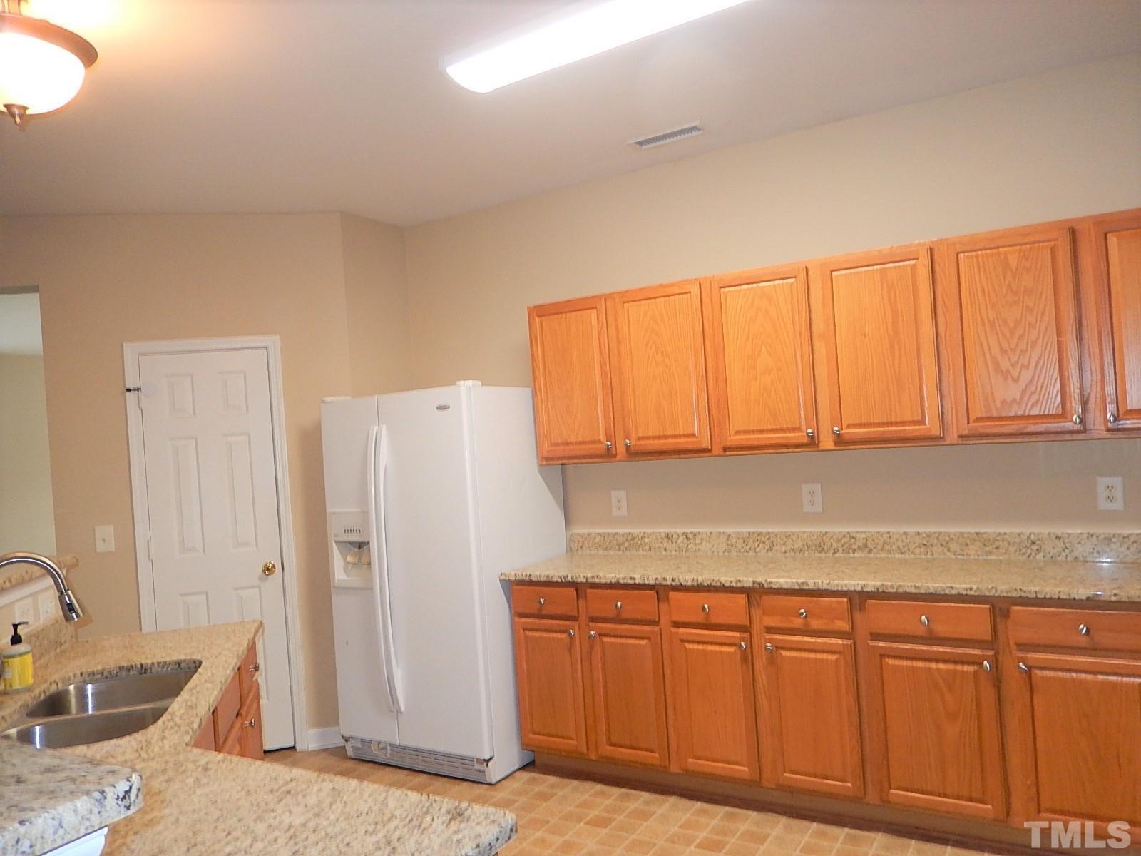 101 Olvera Way Holly Springs, NC 27540 - Photo 13 of 25 a kitchen with stainless steel appliances granite countertop a refrigerator and a sink