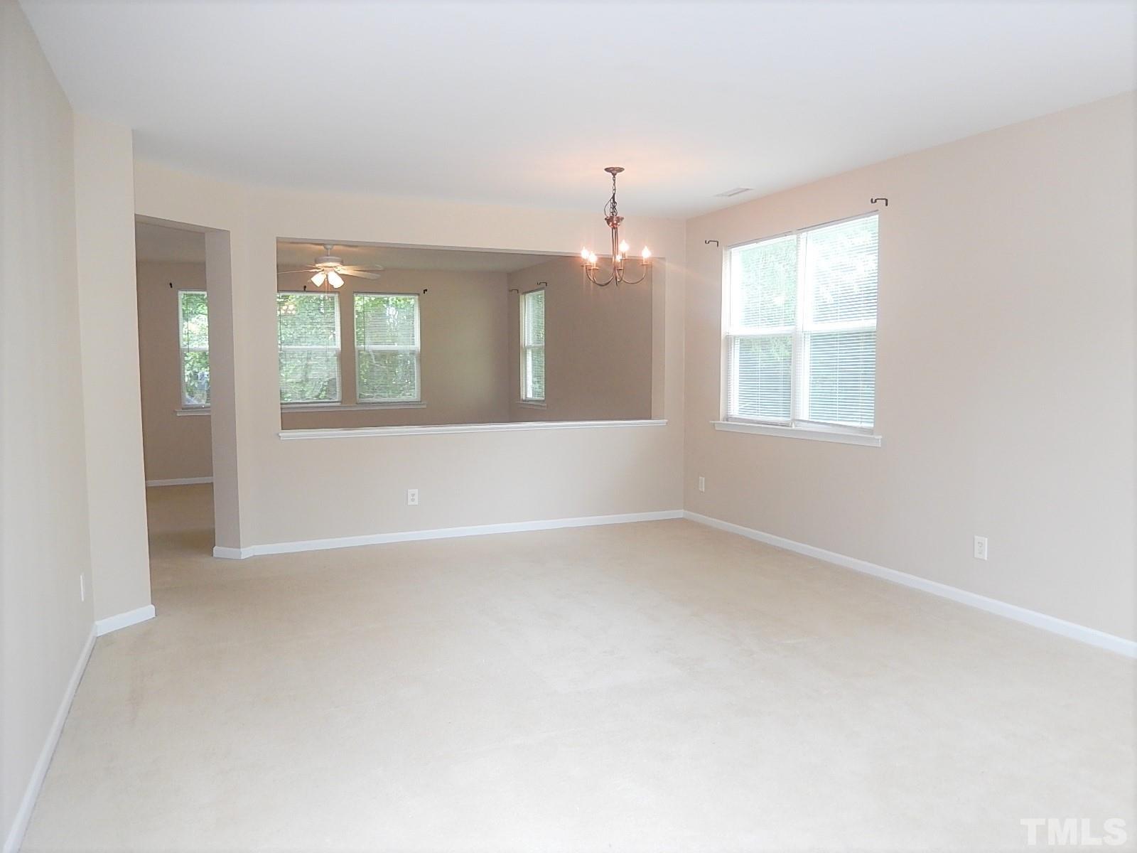 101 Olvera Way Holly Springs, NC 27540 - Photo 2 of 25 an empty room with windows and chandelier