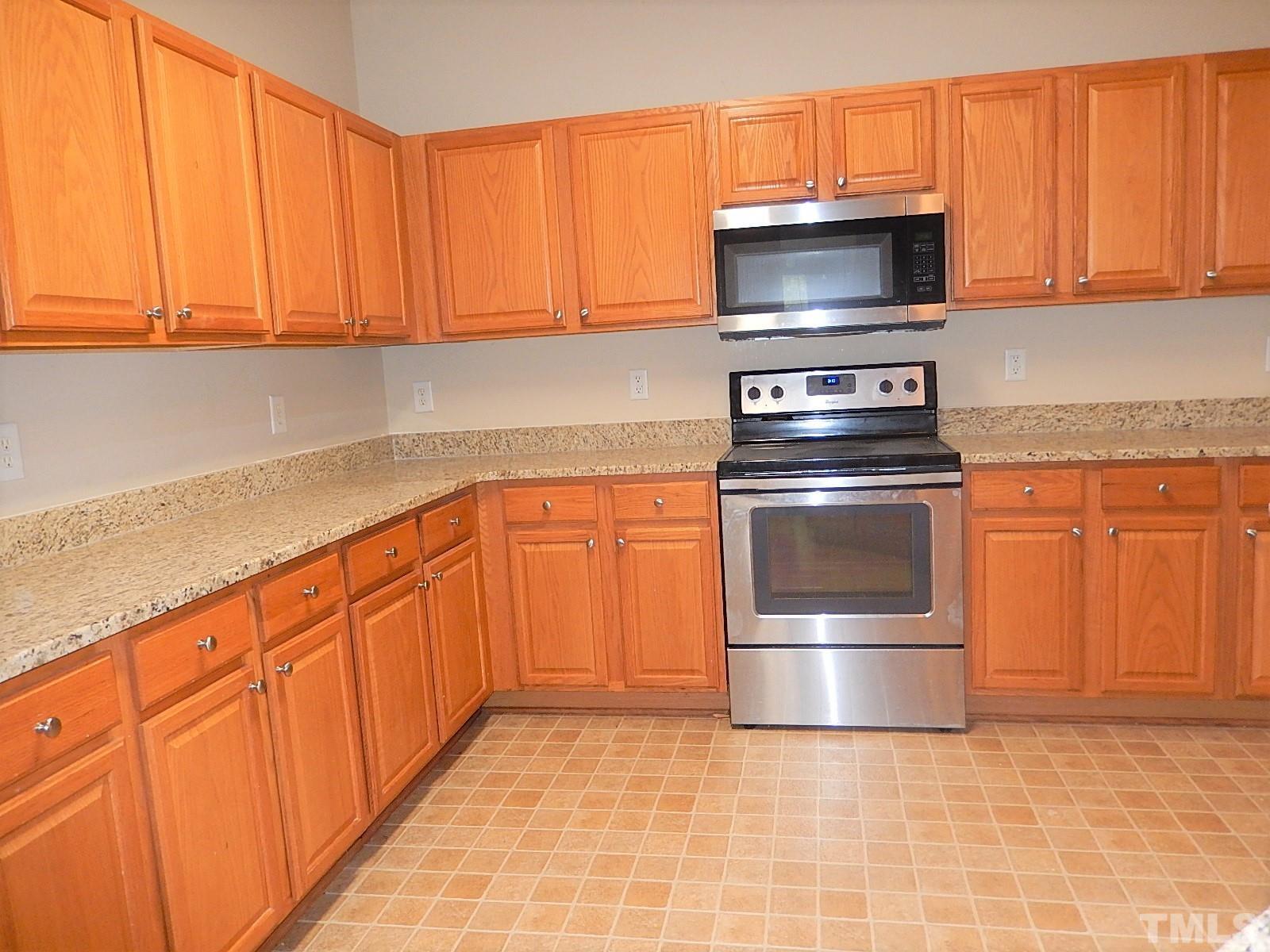 101 Olvera Way Holly Springs, NC 27540 - Photo 7 of 25 a kitchen with granite countertop a stove top oven microwave and cabinets