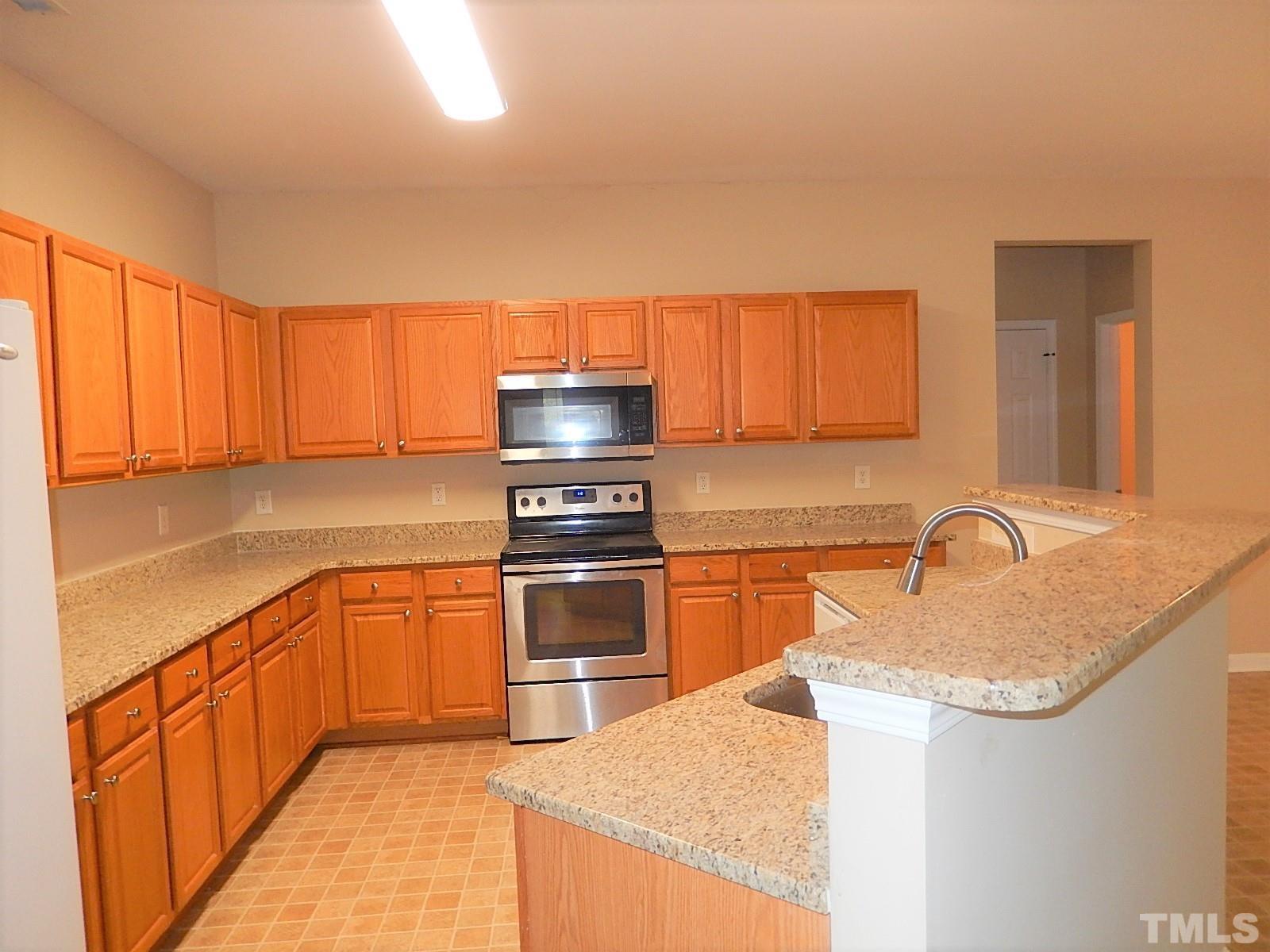 101 Olvera Way Holly Springs, NC 27540 - Photo 10 of 25 a kitchen with stainless steel appliances granite countertop a sink stove and refrigerator
