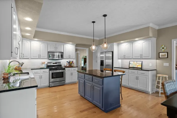 a kitchen with stainless steel appliances kitchen island granite countertop a table and chairs