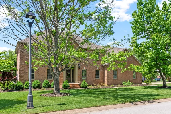 a front view of a house with a yard and trees