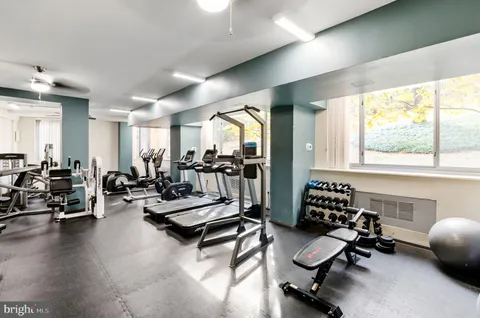 a living room with furniture gym equipment and a large window