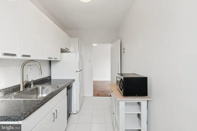 a kitchen with stainless steel appliances granite countertop a sink a microwave refrigerator and a counter top space