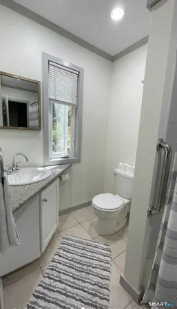 a bathroom with a granite countertop toilet a sink and a mirror