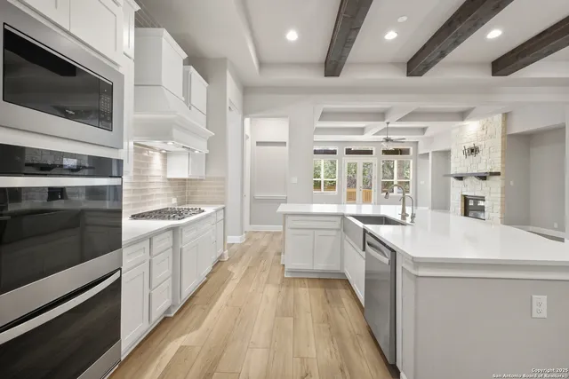 a large white kitchen with sink and stainless steel appliances