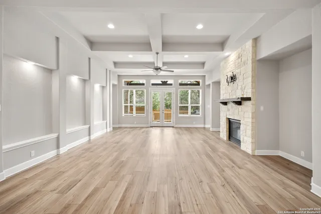 a view of an empty room with wooden floor and a kitchen