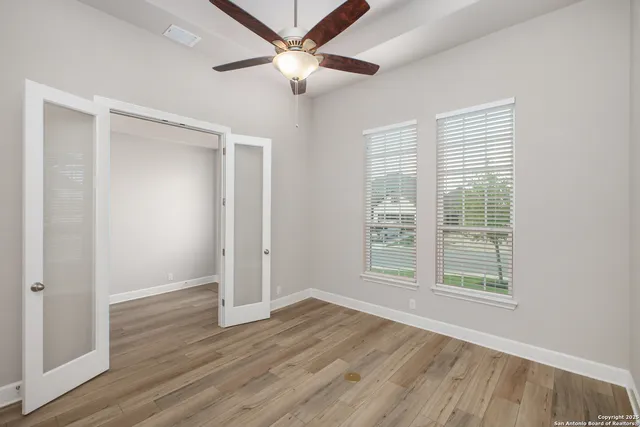 a view of an empty room with wooden floor and a window