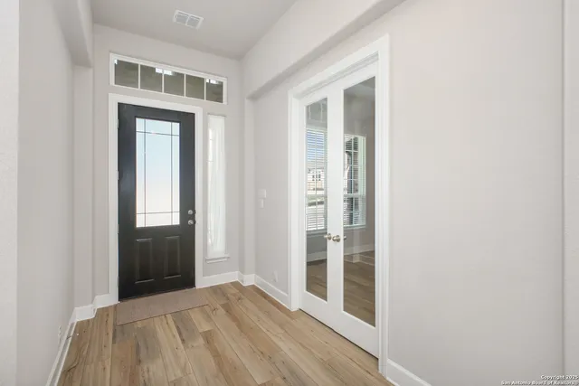 an empty room with wooden floor and windows