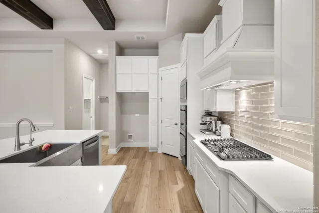 a large kitchen with stainless steel appliances a large counter top a stove and a refrigerator