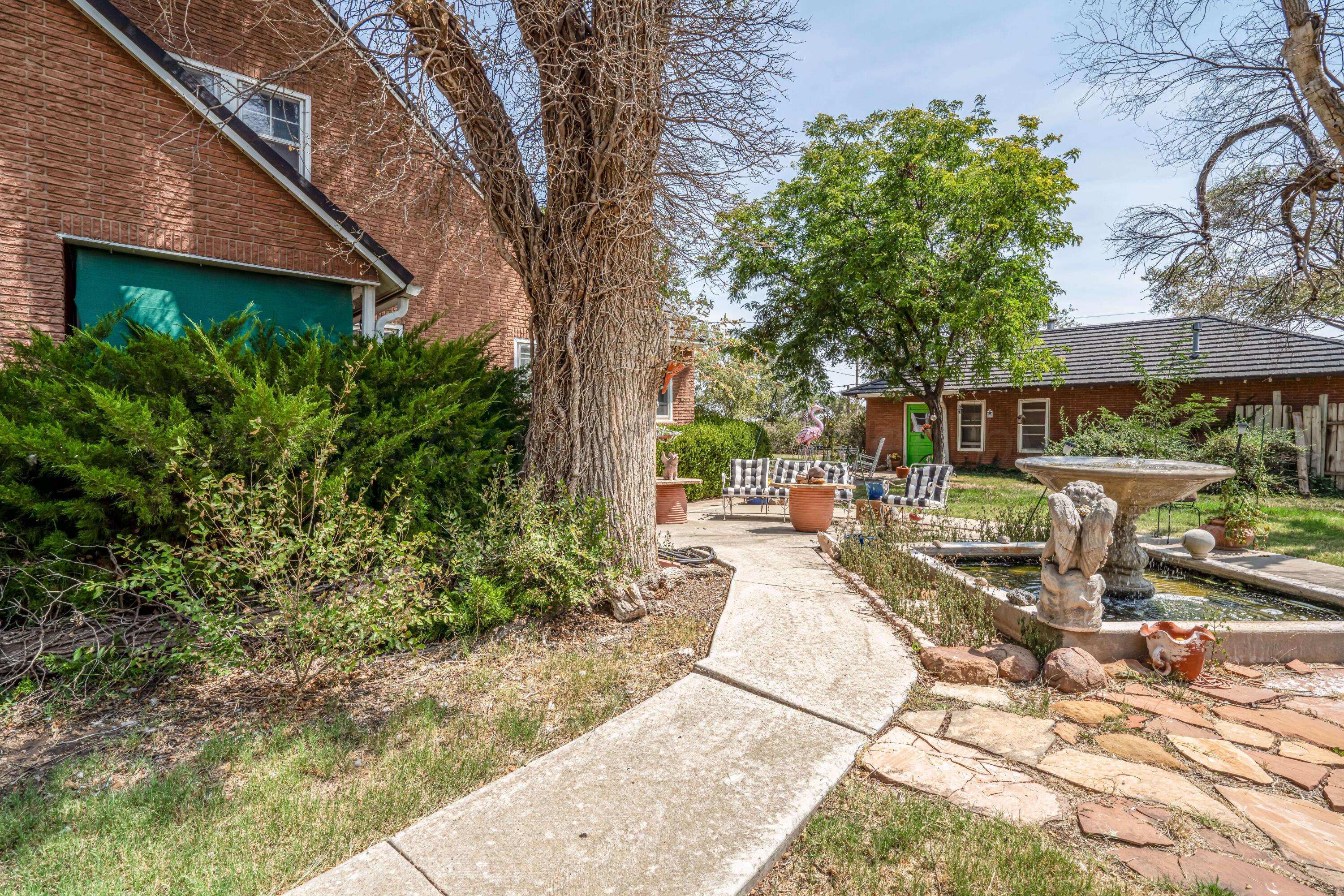 4809 Arden Road Amarillo, TX 79110 - Photo 5 of 34 a view of a patio with table and chairs under an umbrella with large trees