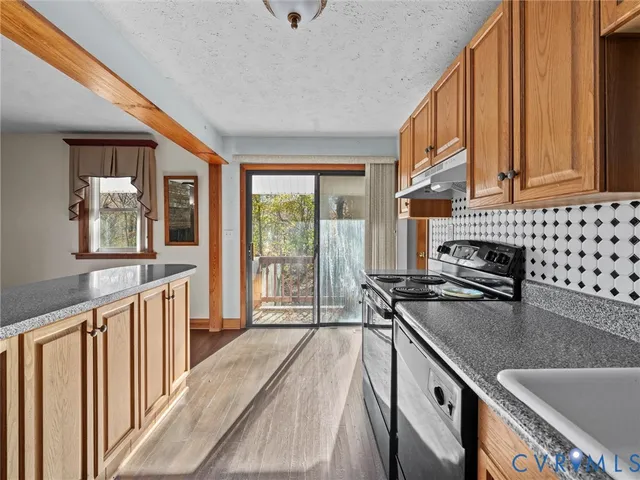 an empty room with wooden floor a ceiling fan and windows