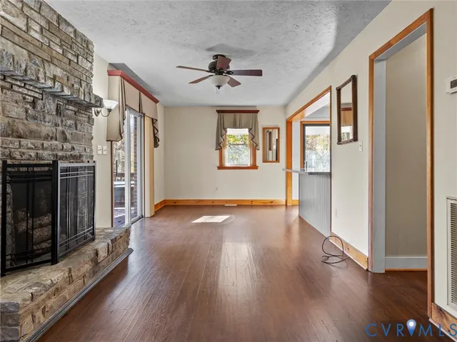 a view of an empty room with wooden floor and a fireplace