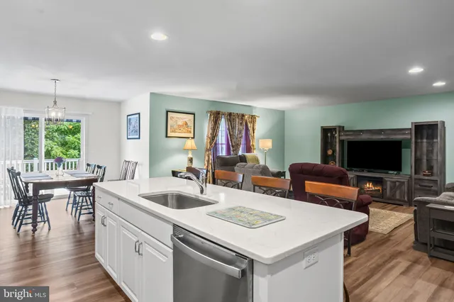 a view of kitchen island a sink wooden floor and a living room