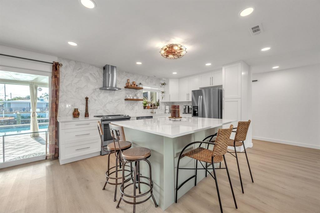 1611 Southwest 3rd Avenue Pompano Beach, FL 33060 - Photo 20 of 35 a kitchen with stainless steel appliances kitchen island granite countertop a dining table chairs and white cabinets