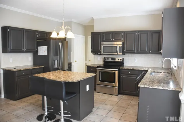 a kitchen with a stove a sink a microwave a refrigerator and chairs