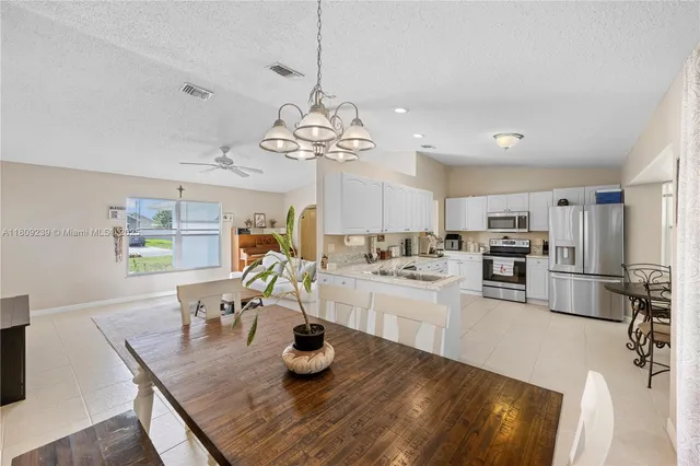 a kitchen with a dining table wooden floor stainless steel appliances and cabinets