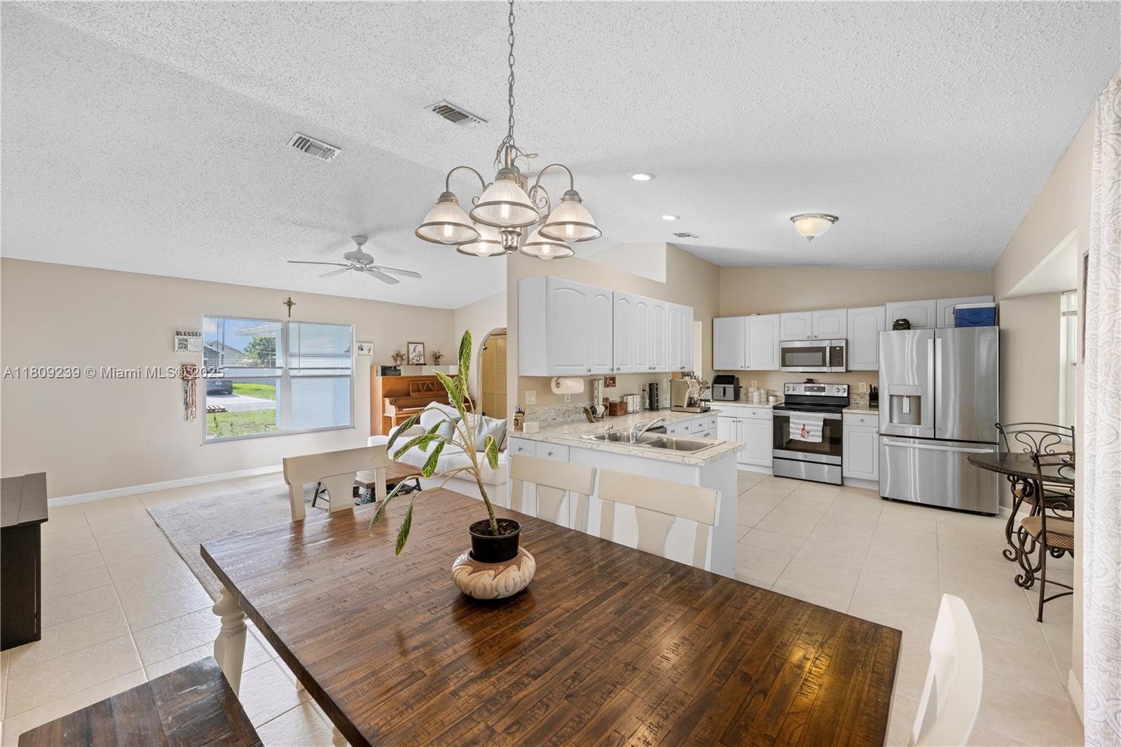 a kitchen with a dining table wooden floor stainless steel appliances and cabinets