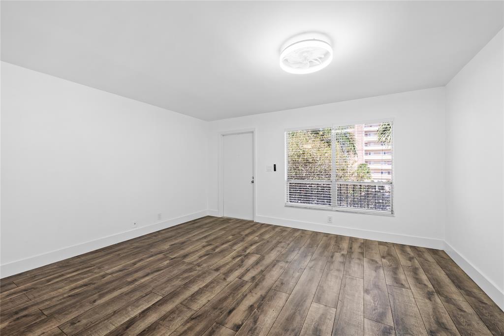 1100 Crystal Lake Drive, Unit 209 Deerfield Beach, FL 33073 - Photo 14 of 34 a view of an empty room with wooden floor and a window