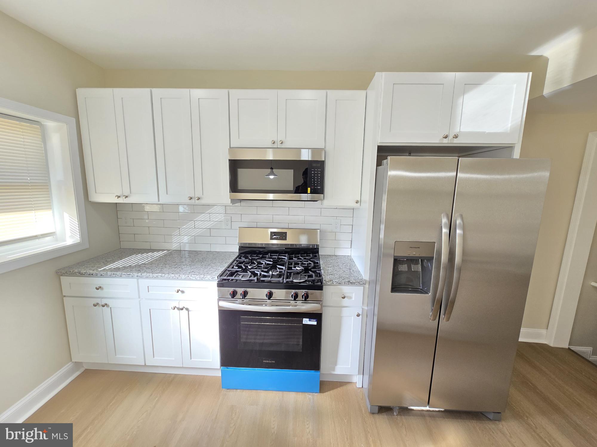 3838 Greenspring Avenue Baltimore, MD 21211 - Photo 6 of 23 a kitchen with white cabinets and stainless steel appliances