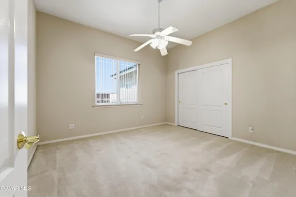 an empty room with a chandelier fan and windows