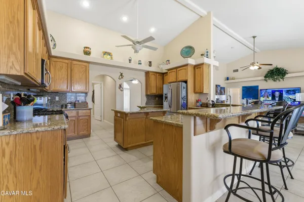 a kitchen with stainless steel appliances kitchen island granite countertop a table chairs and a refrigerator