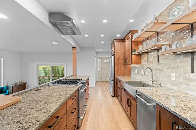 a kitchen with stainless steel appliances granite countertop sink stove and refrigerator