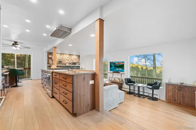 a kitchen with stainless steel appliances kitchen island granite countertop a stove and a wooden floors
