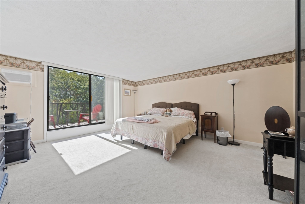 9 Broadway, Unit 305 Saugus, MA 01906 - Photo 13 of 32 a bedroom with a bed a table and large windows