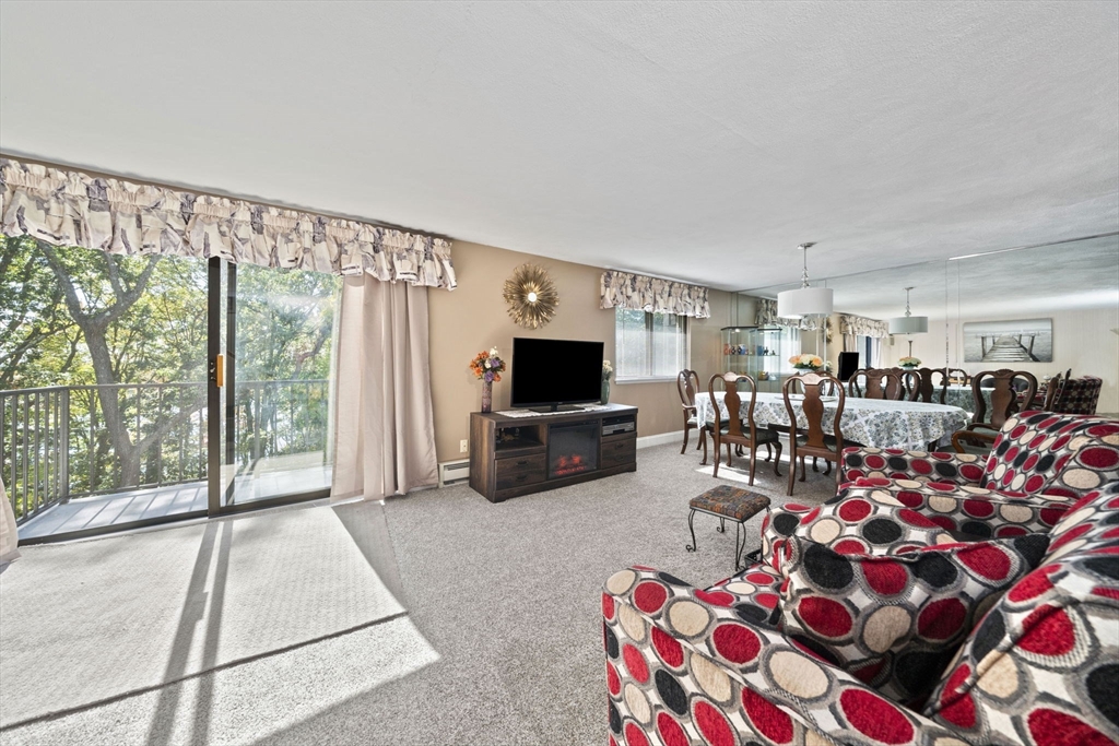 9 Broadway, Unit 305 Saugus, MA 01906 - Photo 7 of 32 a living room with furniture a flat screen tv and a floor to ceiling window