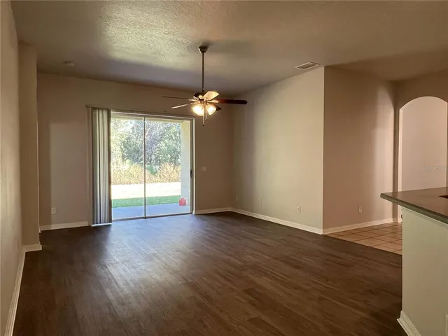 a view of an empty room with wooden floor fridge and a window