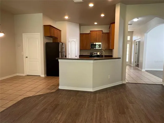 a kitchen with stainless steel appliances granite countertop a refrigerator a sink a stove and a microwave