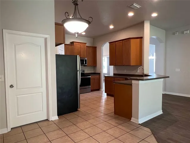 a kitchen with kitchen island granite countertop a refrigerator and a stove top oven
