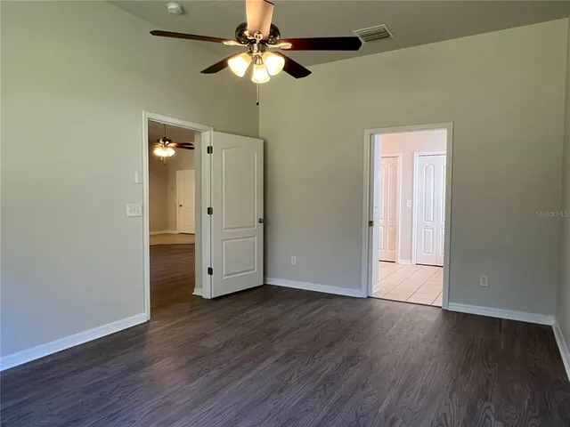 an empty room with wooden floor a ceiling fan and closet