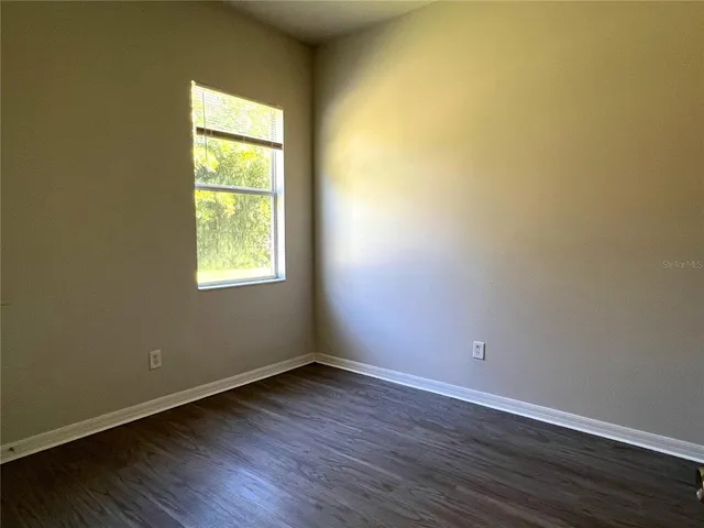 an empty room with wooden floor and a window
