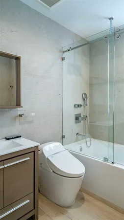 a bathroom with a granite countertop bathtub shower sink vanity and toilet