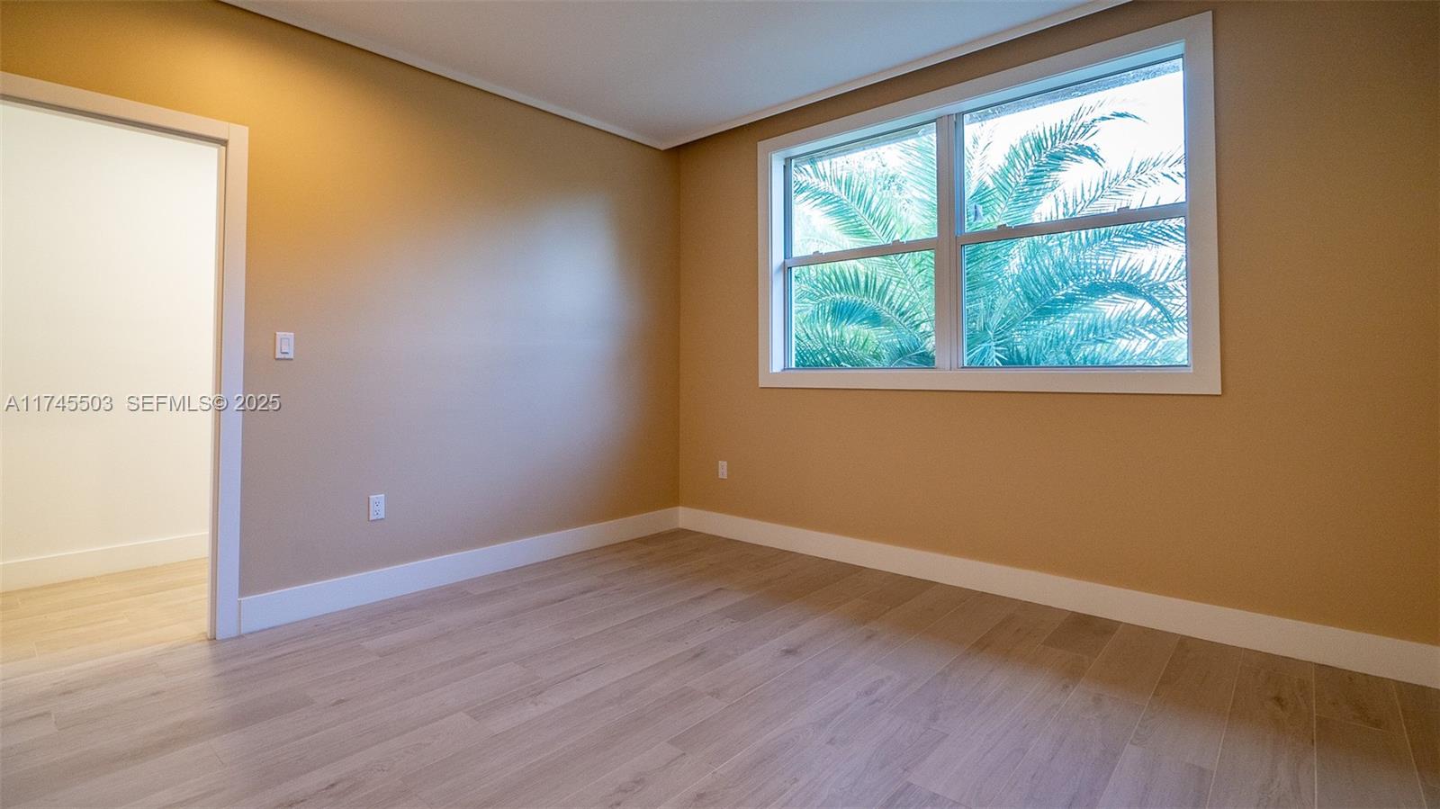 1310 Northeast 117th Terrace, Unit 2 Miami, FL 33161 - Photo 6 of 37 an empty room with wooden floor and windows
