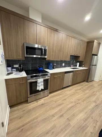 a kitchen with granite countertop a sink a stove top oven and cabinetry