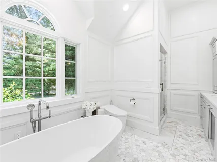 a bathroom with a tub a sink a window and a shower