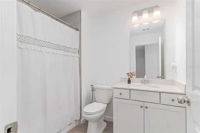 a bathroom with a toilet sink vanity and mirror