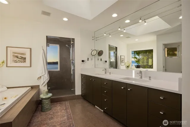 a spacious bathroom with a double vanity sink a toilet a bathtub and shower
