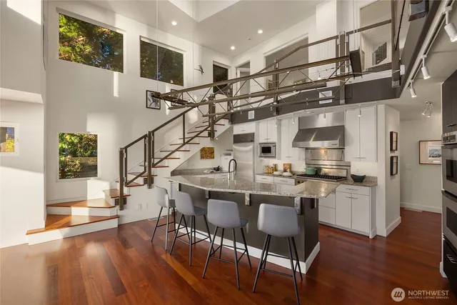 a kitchen with stainless steel appliances granite countertop a table chairs cabinets and wooden floor